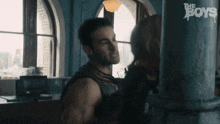a man and a woman are standing next to each other in a room in front of a window .