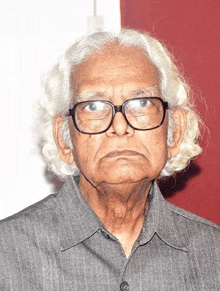 a close up of an older man wearing glasses and a shirt .