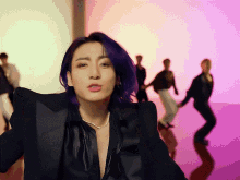 a man with purple hair is wearing a black suit and a necklace