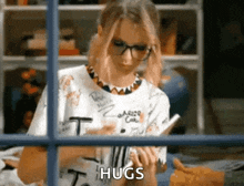 a woman is writing on a piece of paper with the word hugs written on it