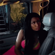 a woman in a pink dress is sitting in the back seat of a car