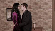 a woman in a purple dress kisses a man in a suit