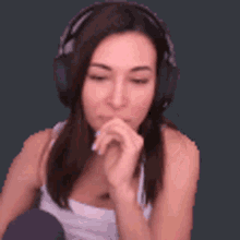 a woman wearing headphones is sitting down with her hand on her chin