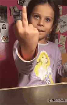 a little girl wearing a rapunzel shirt shows her middle finger