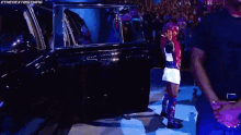 a man and a woman are standing next to each other in front of a limo .
