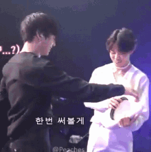 two men are hugging each other on a stage with korean writing on the screen