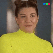 a woman wearing a neon yellow sweater and earrings is smiling and looking at the camera .