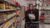 a woman pushing a shopping cart in a grocery store with a sign that says " rice mexican foods fresh produce "