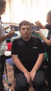 a group of people are taking a picture of a boy 's face with their cell phones