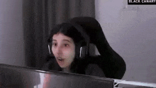 a woman wearing headphones is sitting in a chair in front of a computer monitor .
