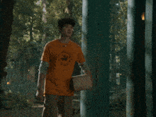 a boy in an orange shirt is standing in the doorway of a building
