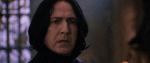 a man with long black hair looks at the camera with a serious look on his face