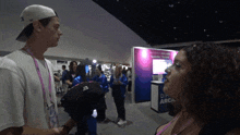 a woman talks to a man in front of a sign that says different arca