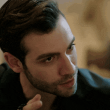 a close up of a man 's face with a beard and black shirt