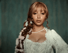 a woman wearing a white dress and pearls is looking at the camera