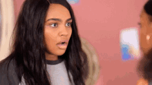 a woman with long black hair is making a surprised face while looking at another woman .