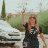 a woman wearing a black adidas t-shirt stands in front of a white van