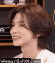 a close up of a young man 's face with the words yeosang - he 's fooling you written below him