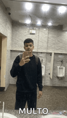 a man taking a picture of himself in a public restroom with the word molto below him