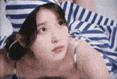 a woman in a blue and white striped dress is laying on a bed