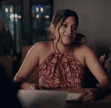 a woman in a floral top sits at a table smiling