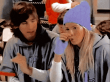 a girl wearing a purple beanie and gloves talks to a boy wearing a hoodie with the letter a on it