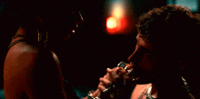 a man kissing a woman 's hand with a red light in the background