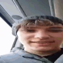 a young man wearing a hat with ears is smiling in a car .