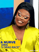 a woman wearing a yellow shirt and earrings is smiling while talking on a television show .