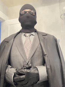 a man in a suit and gloves is wearing a black mask