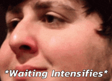 a close up of a man 's face with the words " waiting intensifies " written below it