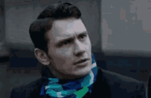 a man wearing a scarf around his neck and a suit is making a funny face .