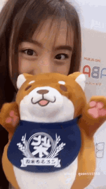 a woman is holding a stuffed animal with a blue bandana around its neck that says mushrooms