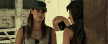 two women are standing next to each other and one of them is wearing a hat that says army on it