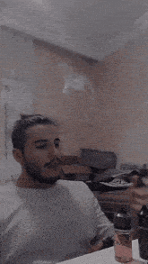 a man is sitting at a table with a bottle of ome on the table
