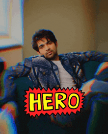 a man sitting on a couch with a sticker that says hero on it