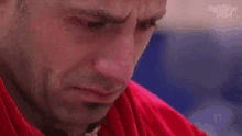 a close up of a man 's face with a red shirt on and a beard .