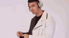 a young man wearing headphones and a white jacket is dancing