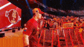 a man in a red shirt and hat is walking in front of a crowd .