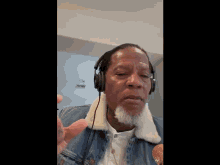 a man wearing headphones and a denim jacket is giving a thumbs up