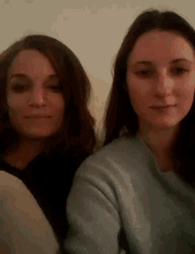 two women are standing next to each other and one is wearing a blue sweater
