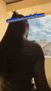a woman is looking out a window with a sign that says assalamualaikum