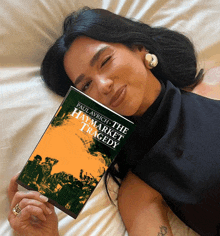 a woman laying on a bed holding a copy of the haymarket tragedy by paul avrich