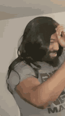 a man with long hair and a beard is wearing a blue shirt that says ' true max ' on it