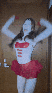 a woman wearing a white top and a red skirt is standing in front of a door