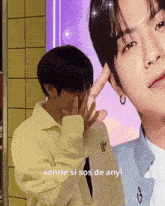 a man is covering his face with his hand and another man is behind him .