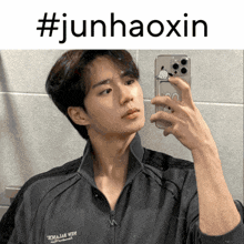 a young man is taking a picture of himself in a mirror with the hashtag #junhaoxin