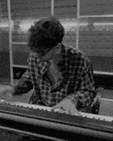 a man in a plaid shirt plays a keyboard