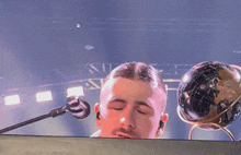 a man singing into a microphone with a globe in the foreground