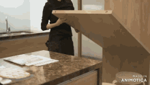 a woman holds a piece of wood over a kitchen counter that is made in animatica